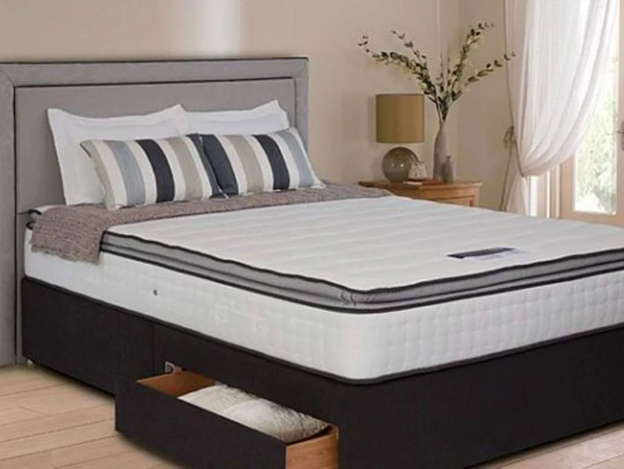 A bare mattress on a bed base in a bright bedroom, ready for cleaning