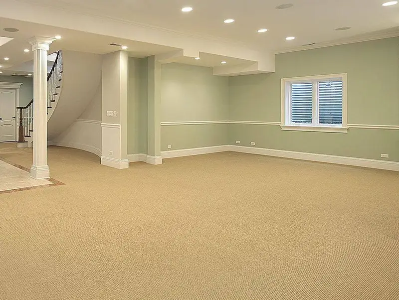 An empty carpeted living area with a staircase beyond