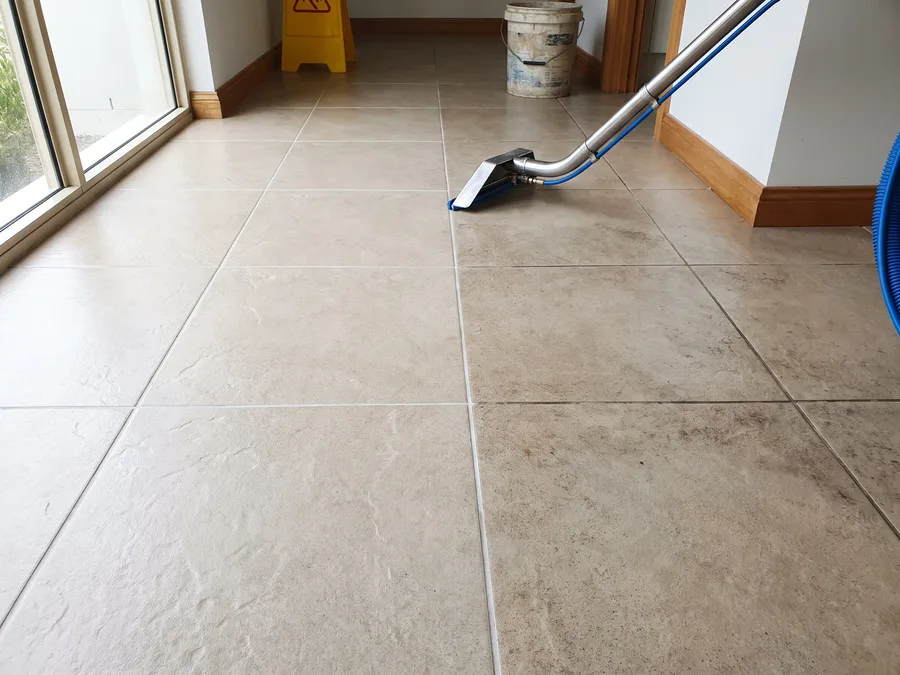 Tile and grout cleaning in progress, half the beige tiled floor already bright