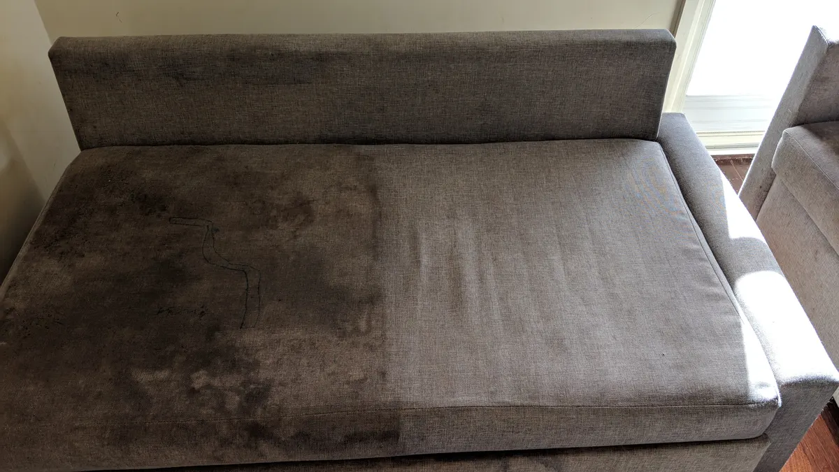 An upholstery clean halfway through, the cleaned half visibly lighter than the soiled half